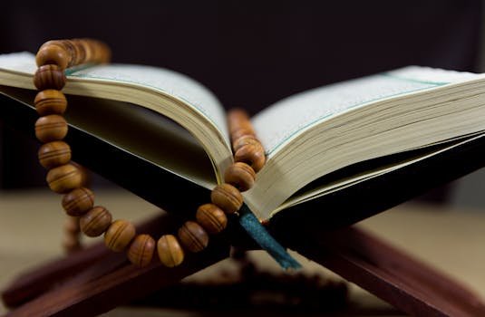 Home An open Quran with prayer beads on a wooden stand, symbolizing faith and spirituality.